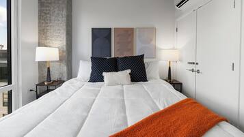 Une chambre d’hôtel avec un grand lit, deux tables de chevet avec des lampes, une armoire et des œuvres d’art accrochées au mur.