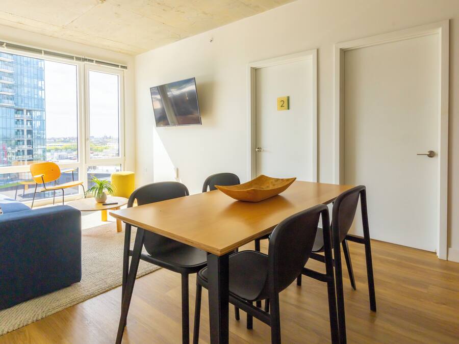 A modern living space with a dining area, a sofa, a TV, and a city view.