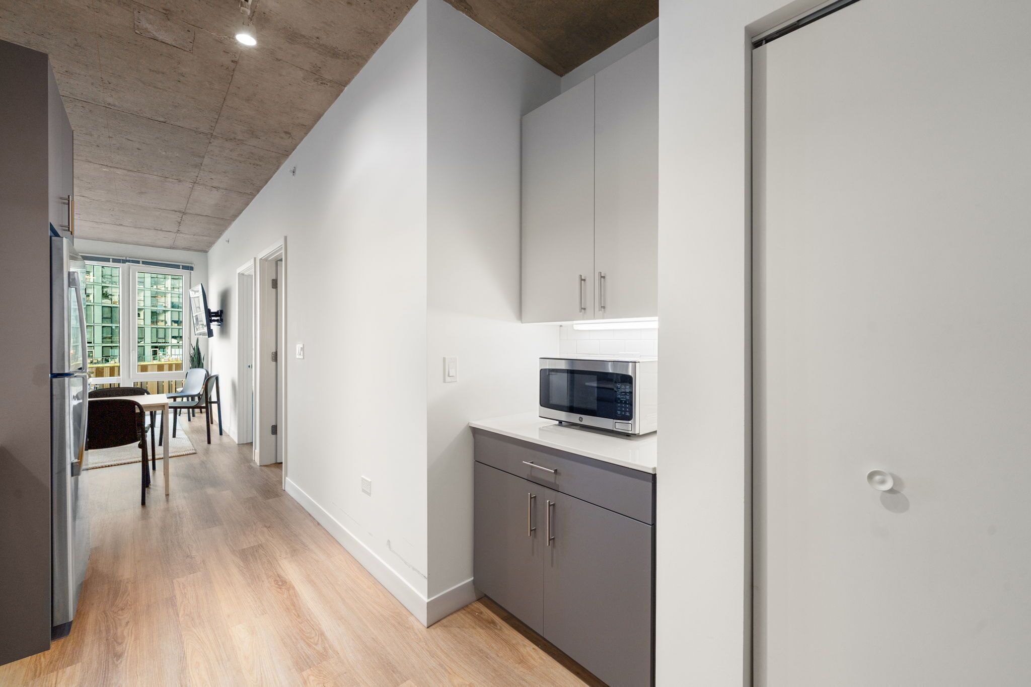 Una cucina moderna con mobili grigi, un forno a microonde e un pavimento in legno.
