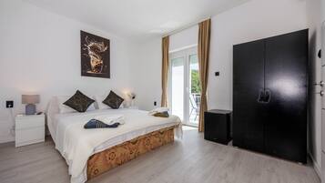 Un dormitorio con una cama, una mesita de noche, un armario negro y una puerta que da a un balcón.