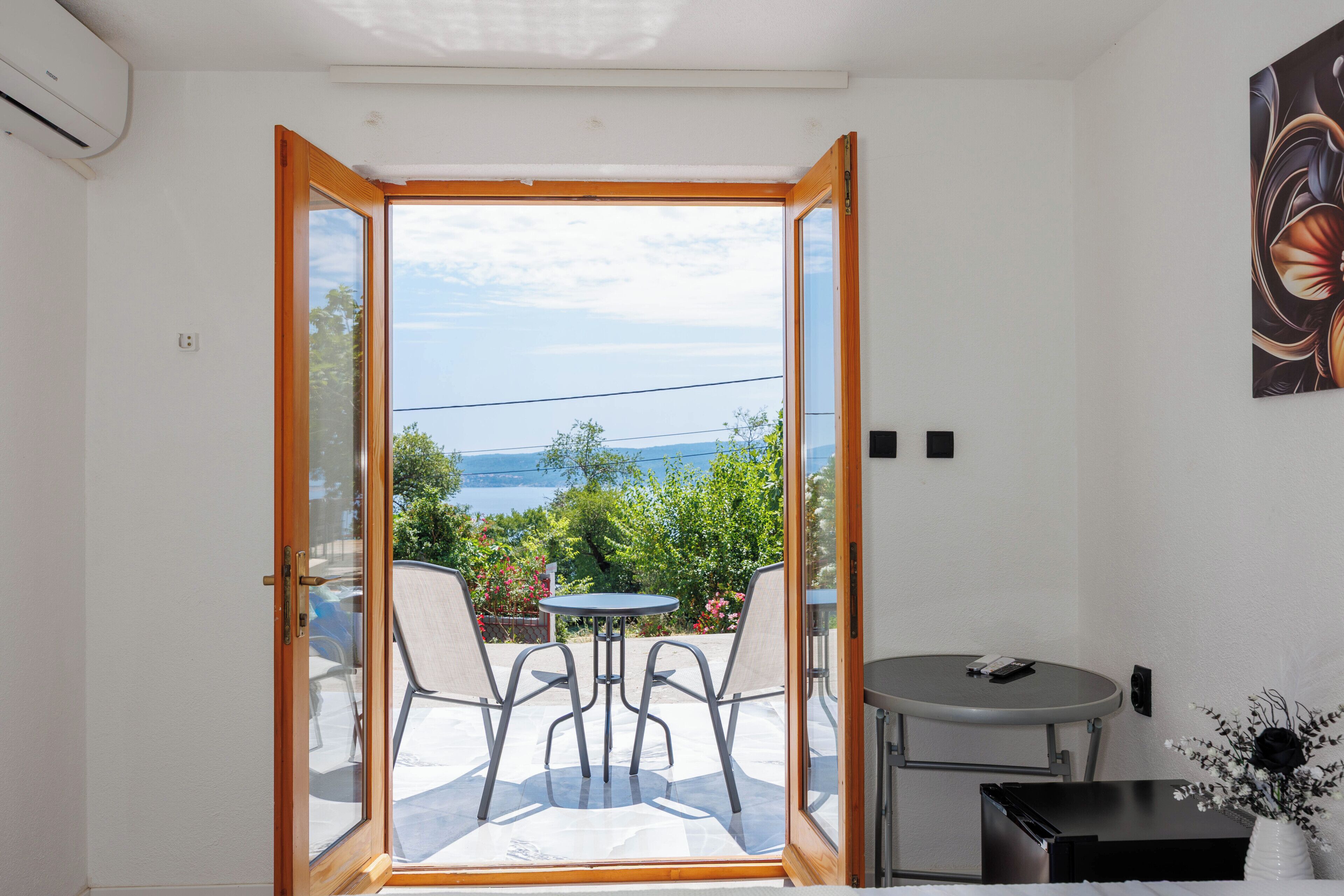 Une pièce dotée d’une porte-fenêtre coulissante donnant sur un espace extérieur aménagé avec une table et des chaises.