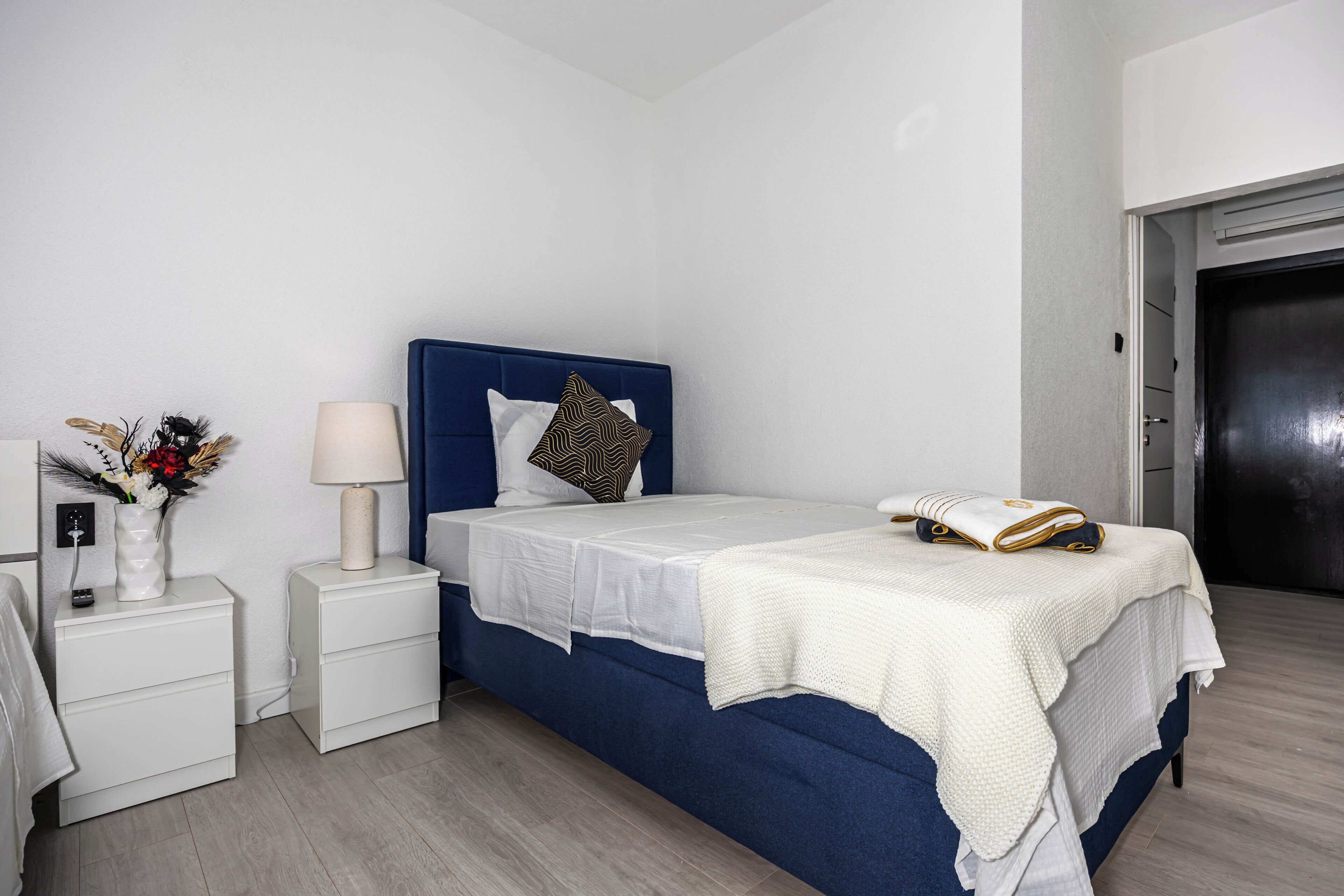 A bedroom with a bed, nightstands, a lamp, and a vase with flowers.