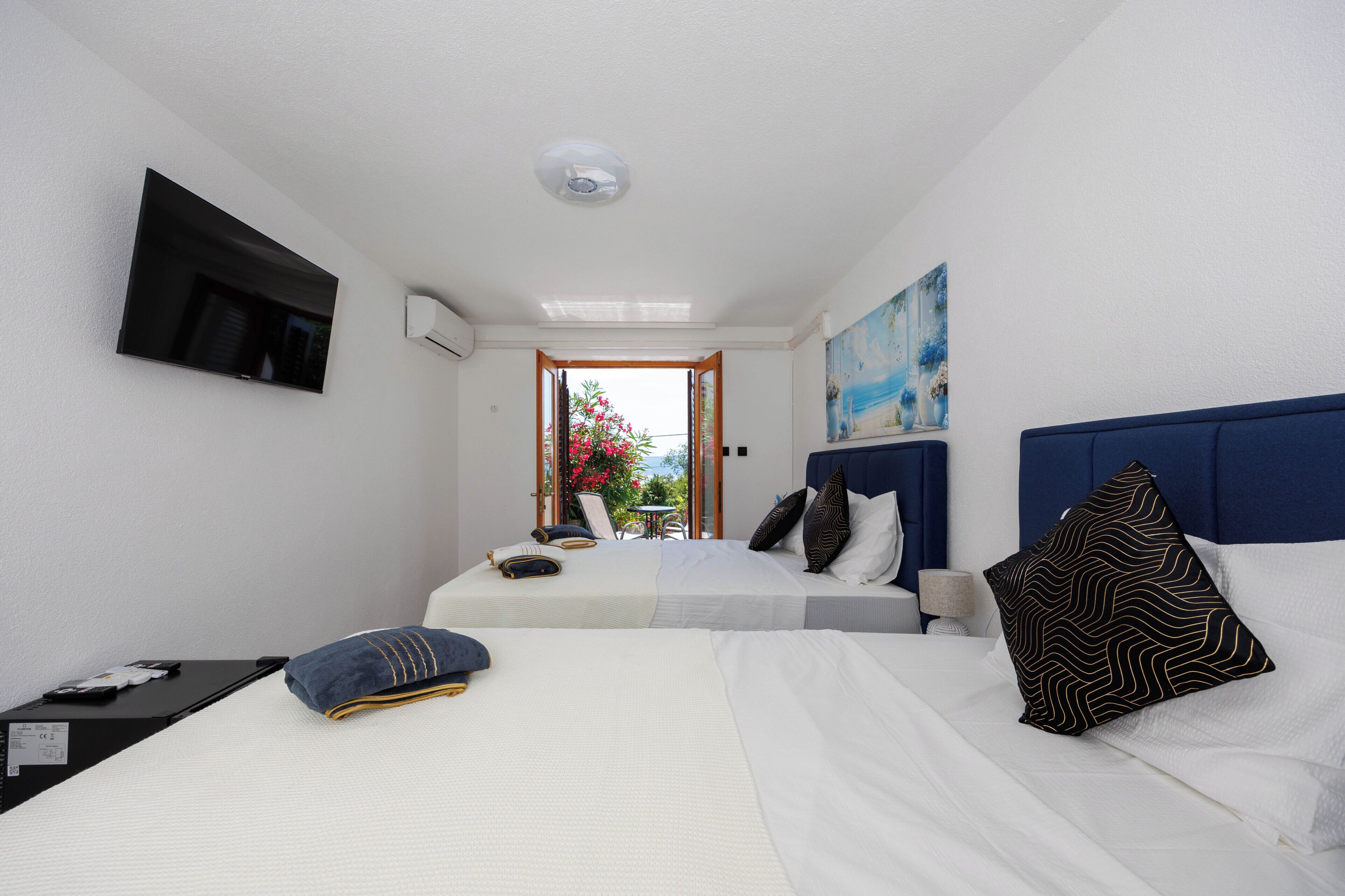 A hotel room with two beds, a TV mounted on the wall, and a painting above the headboard.