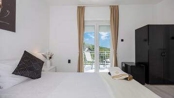A hotel room with a bed, a nightstand, a black wardrobe, and a balcony with a view.