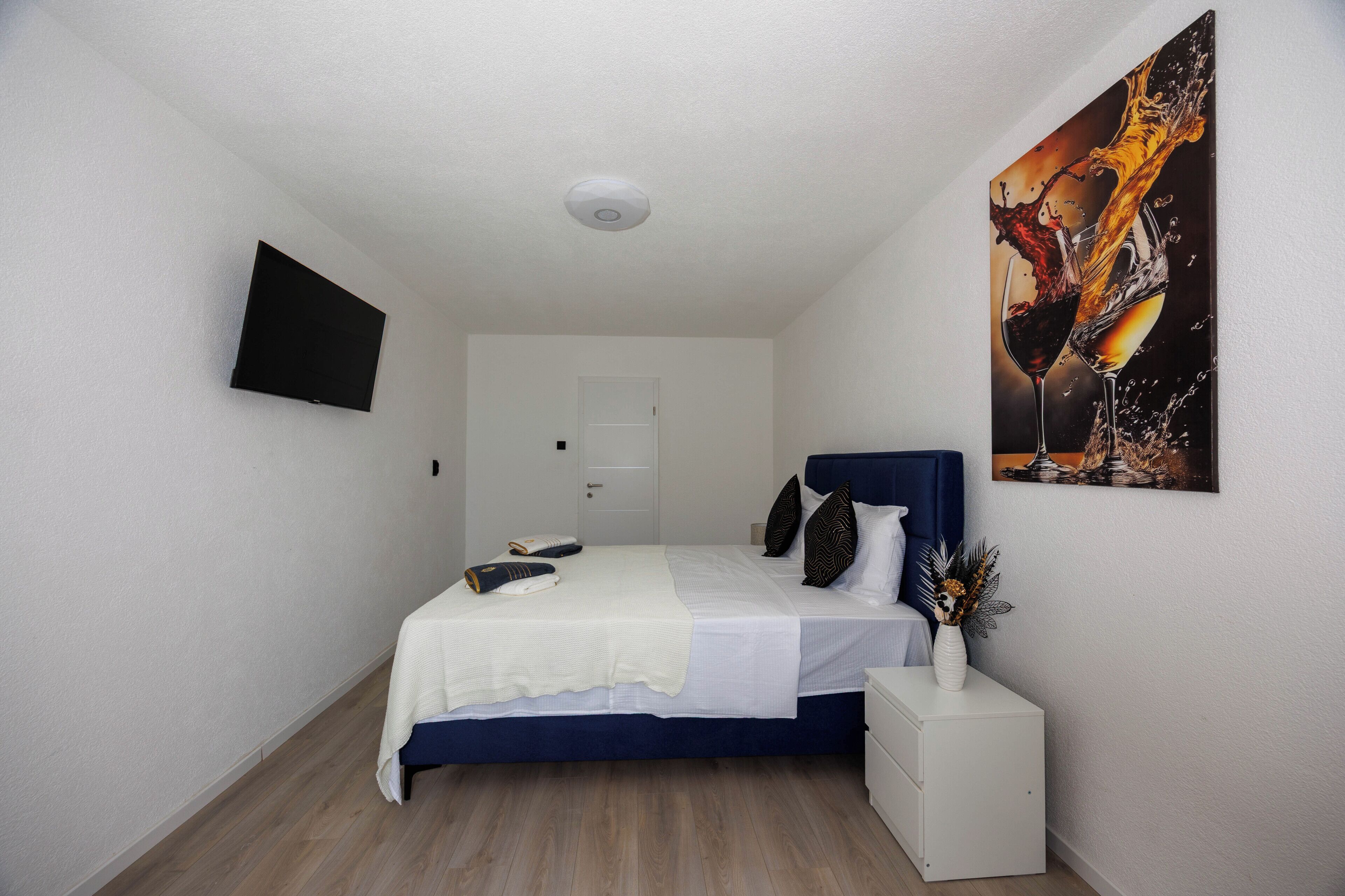 Une chambre à coucher avec un lit, une table de chevet, une commode et un tableau accroché au mur.