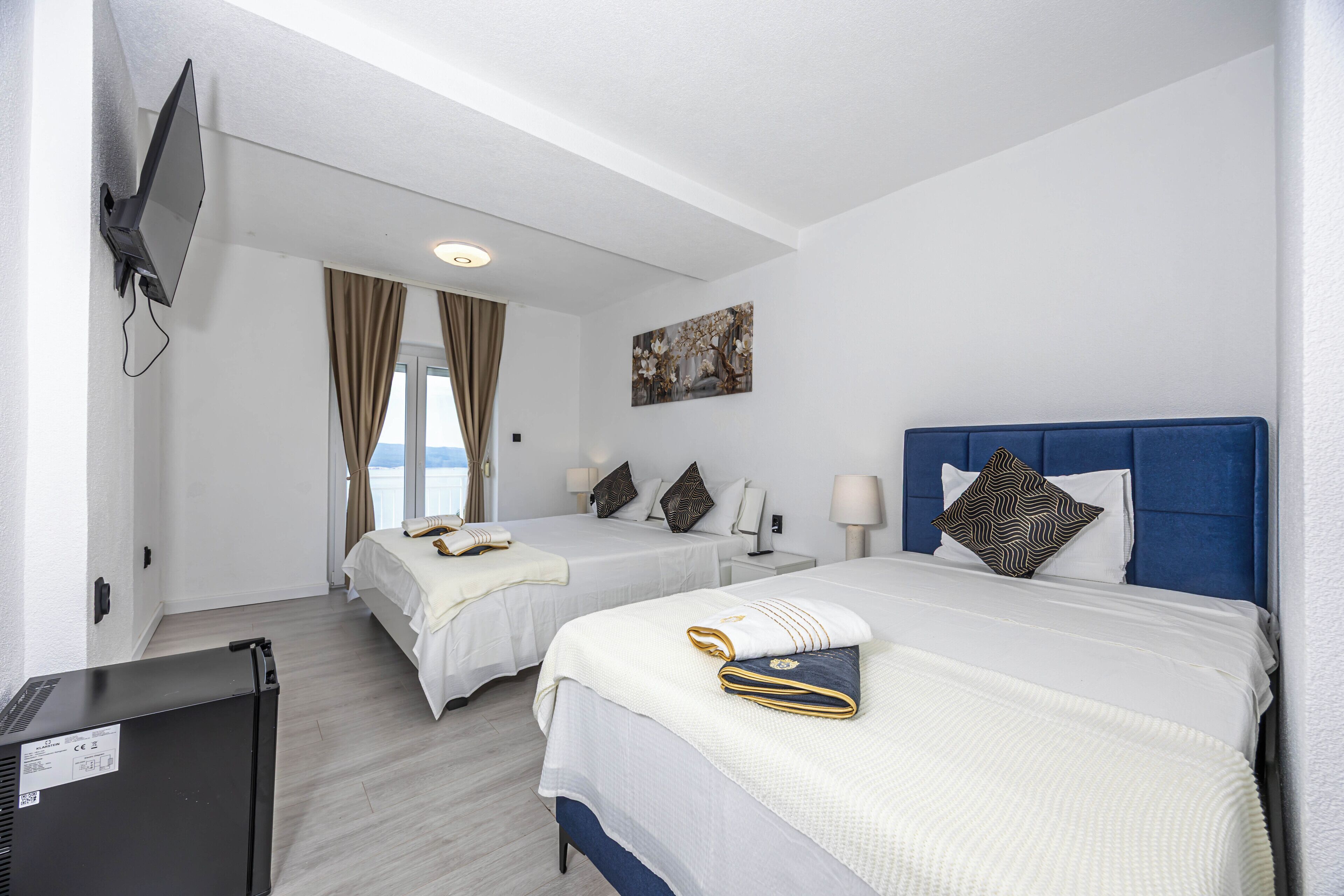 Habitación de hotel con dos camas, un televisor y un cuadro en la pared.