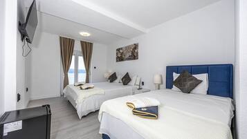 Habitación de hotel con dos camas, un televisor y un cuadro en la pared.
