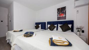 Una habitación de hotel con dos camas, ropa de cama blanca, cabeceros azules y almohadas decorativas.