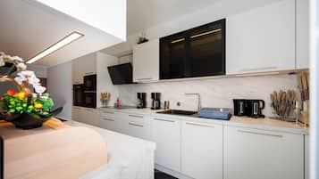 Una cocina moderna con armarios blancos, encimera negra, pileta y cafetera.