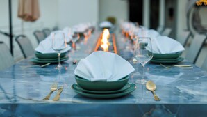 Una mesa de comedor dispuesta con platos verdes, servilletas blancas y cubiertos dorados.