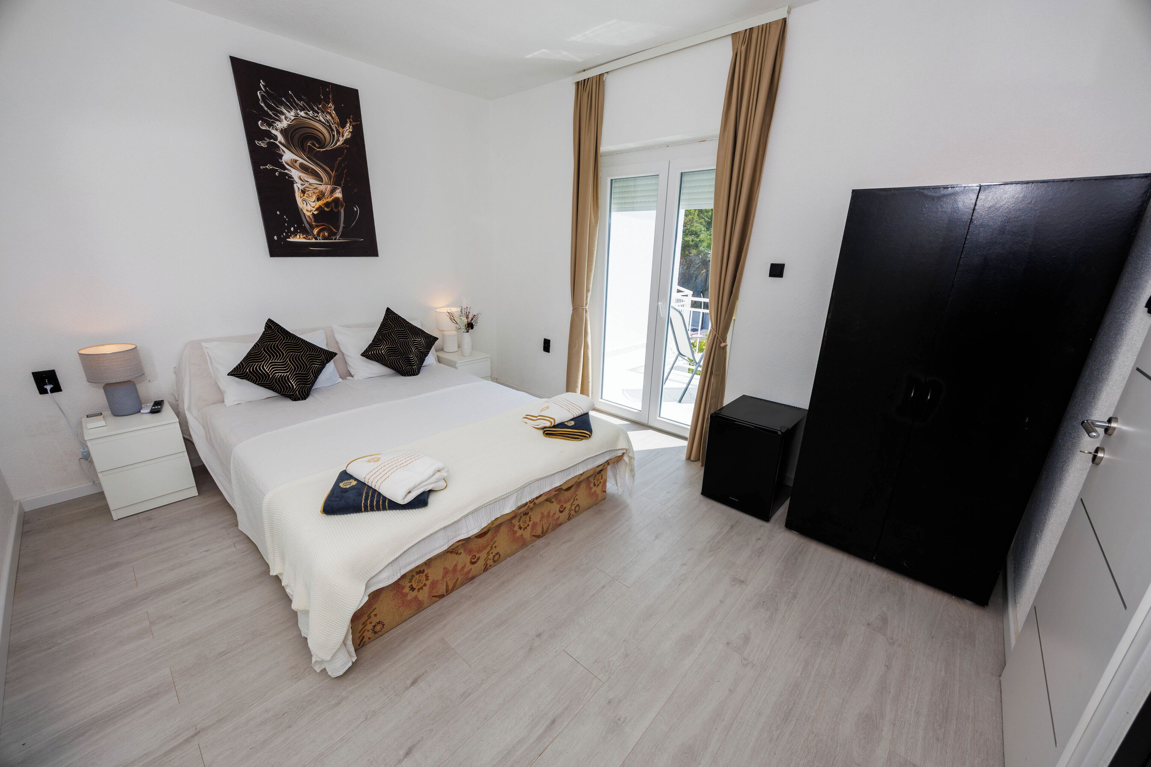 A bedroom with a bed, bedside tables, a wardrobe, and a sliding glass door to the outside.