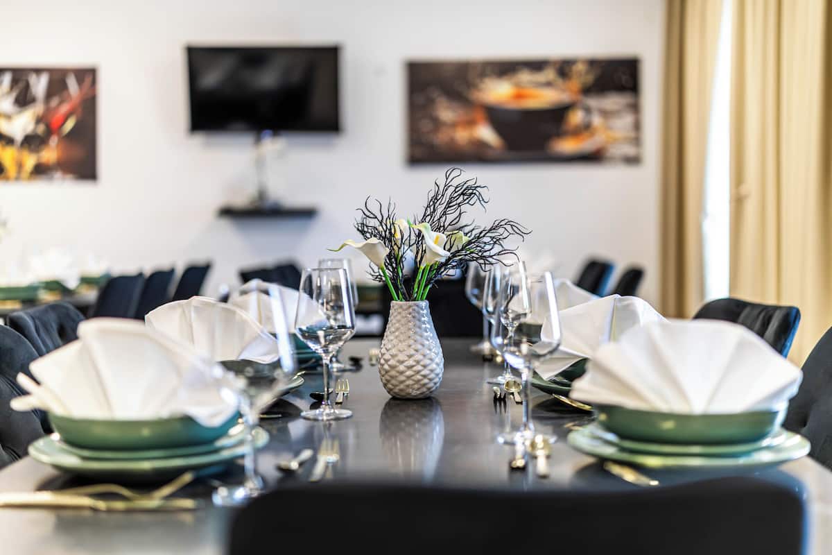 Una mesa de comedor dispuesta con platos, vasos y un florero con flores.