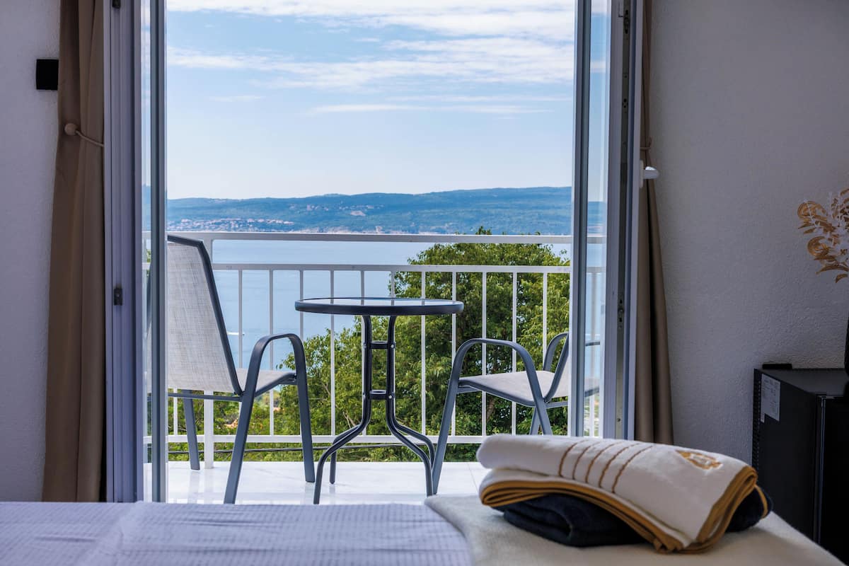 Una habitación de hotel con balcón, cama, mesa y sillas.