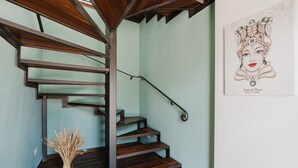 A spiral staircase with dark wood steps and metal railings, a vase of dried plants, and a framed artwork on the wall. - Room 'Maidda' with Shared Garden, Wi-Fi and Air Conditioning (Rilievo)