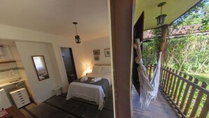 A bedroom with a bed, bedside lamp, and a view of a garden through a balcony. - Hospedagem Country Inn  (Nova Friburgo)