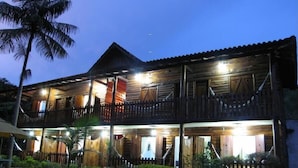 A two-story wooden building with balconies, a garden, and a palm tree. - Hospedagem Country Inn  (Nova Friburgo)