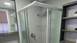 A modern bathroom with a glass-enclosed shower, a toilet, and a sink with a mirror above it.