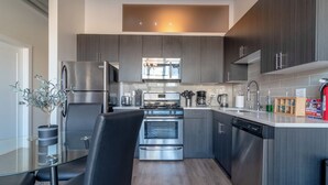 Una cocina moderna con electrodomésticos de acero inoxidable, armarios de madera oscura y una mesa de comedor de vidrio.