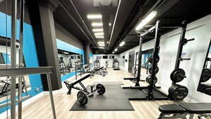 Un gimnasio con diversos equipos de ejercicio, incluyendo bancos de pesas, jaulas de sentadilla y cintas de correr.