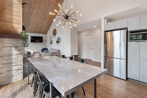 A modern kitchen with a large island, stainless steel appliances, and a unique ceiling light fixture. - Ultimate Comfort with Spa | Le Villa Joie (Saint-Côme)