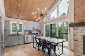 Una cocina moderna con techo de madera, ventanas amplias y una zona de comedor con sillas.