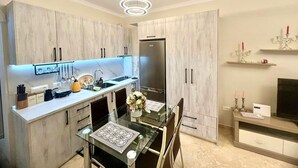 A modern kitchen with a glass dining table, stainless steel appliances, and light wood cabinetry. - Anna Seaview Cozy 1-Studio Apartment in charming Durres with Wi Fi, AC (Durres)