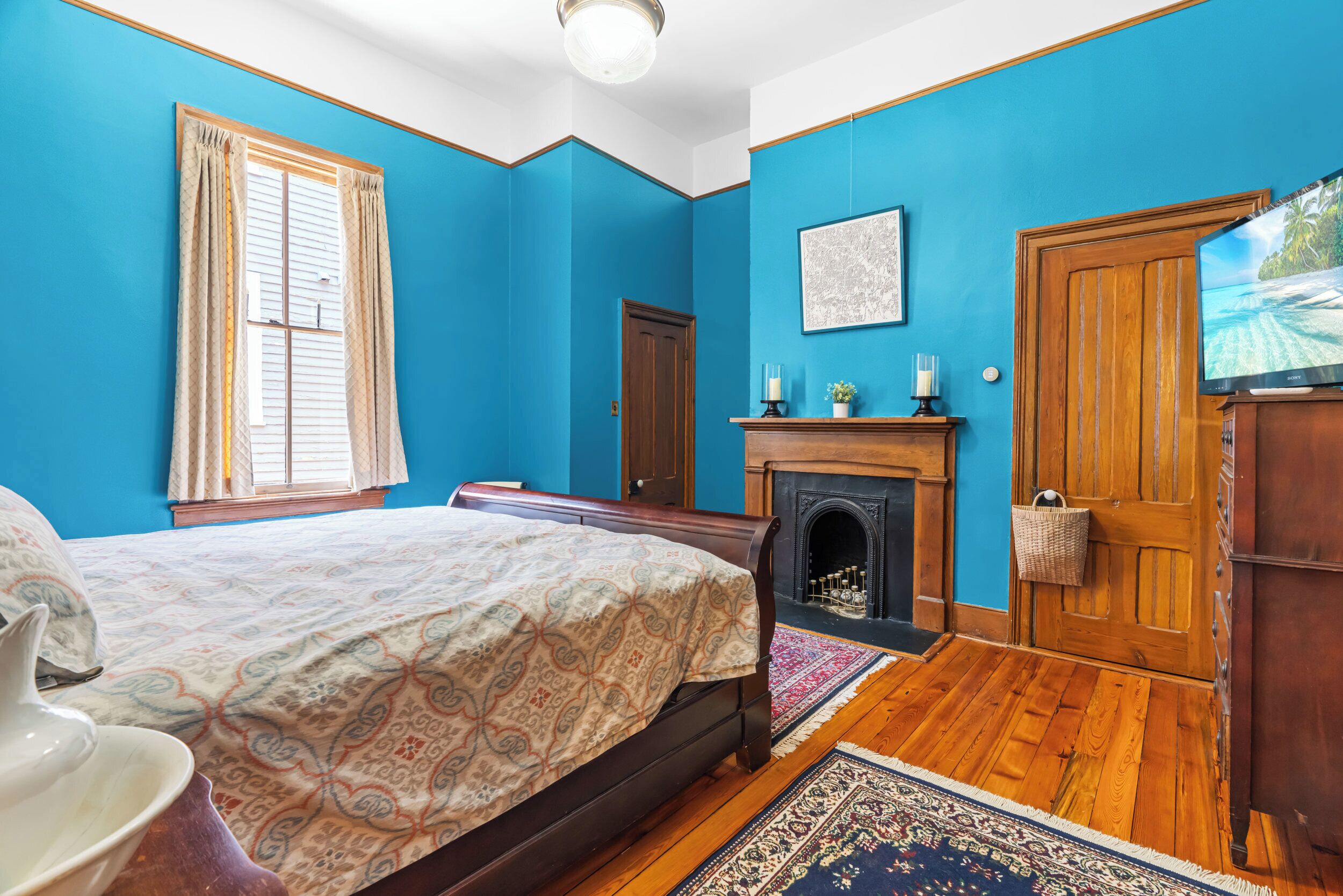 A bedroom with a bed, a fireplace, a television, and a door.