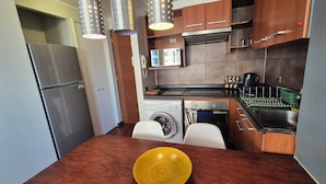 Una cocina compacta con un refrigerador de acero inoxidable, un microondas, una estufa, un fregadero y una lavadora.