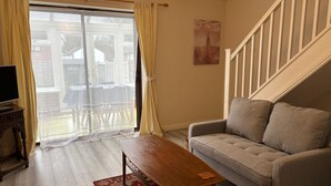 A living room with a sofa, a wooden coffee table, a TV, and a sliding glass door leading to an outdoor area. - Budget Carlisle Home for 4 | Parking & Garden (Carlisle)