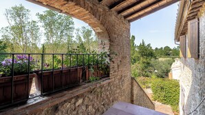 A stone balcony with a wooden railing overlooking a garden with various plants and flowers. -  Casa La Cedrina Pool Lornano (Monteriggioni)