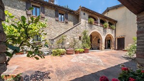 A courtyard with stone walls, arched doorways, and potted plants. -  Casa La Cedrina Pool Lornano (Monteriggioni)