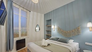 A bedroom with a bed, a window with curtains, a wall-mounted macrame piece, and a small table. - Apartment in the Center of Paris-sacre Coeur (Paris)