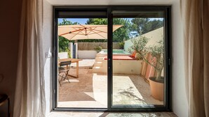 A sliding glass door leading to an outdoor patio with a table, chairs, and a large umbrella.