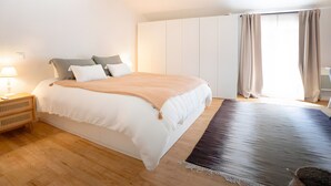 A bedroom with a bed, bedside table, and a large window with curtains.