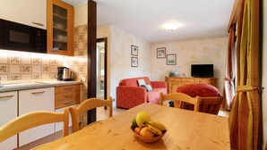 A compact living space with a kitchen, dining area, and a red sofa. - Apartment '2' with Mountain View, Balcony and Wi-Fi (Livigno)