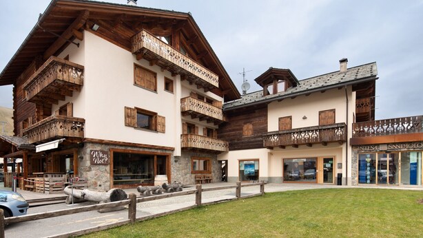 A multi-story building with wooden balconies, stone accents, and a sign reading 'Why Not?' - Apartment '2' with Mountain View, Balcony and Wi-Fi (Livigno)