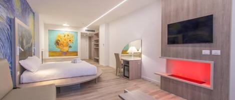 Una camera d'albergo moderna con un letto, una scrivania, una sedia, una televisione e opere d'arte alle pareti.