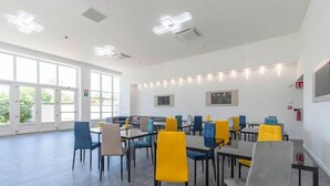 Una habitación amplia con varias mesas y sillas, ventanas grandes e iluminación en el techo.
