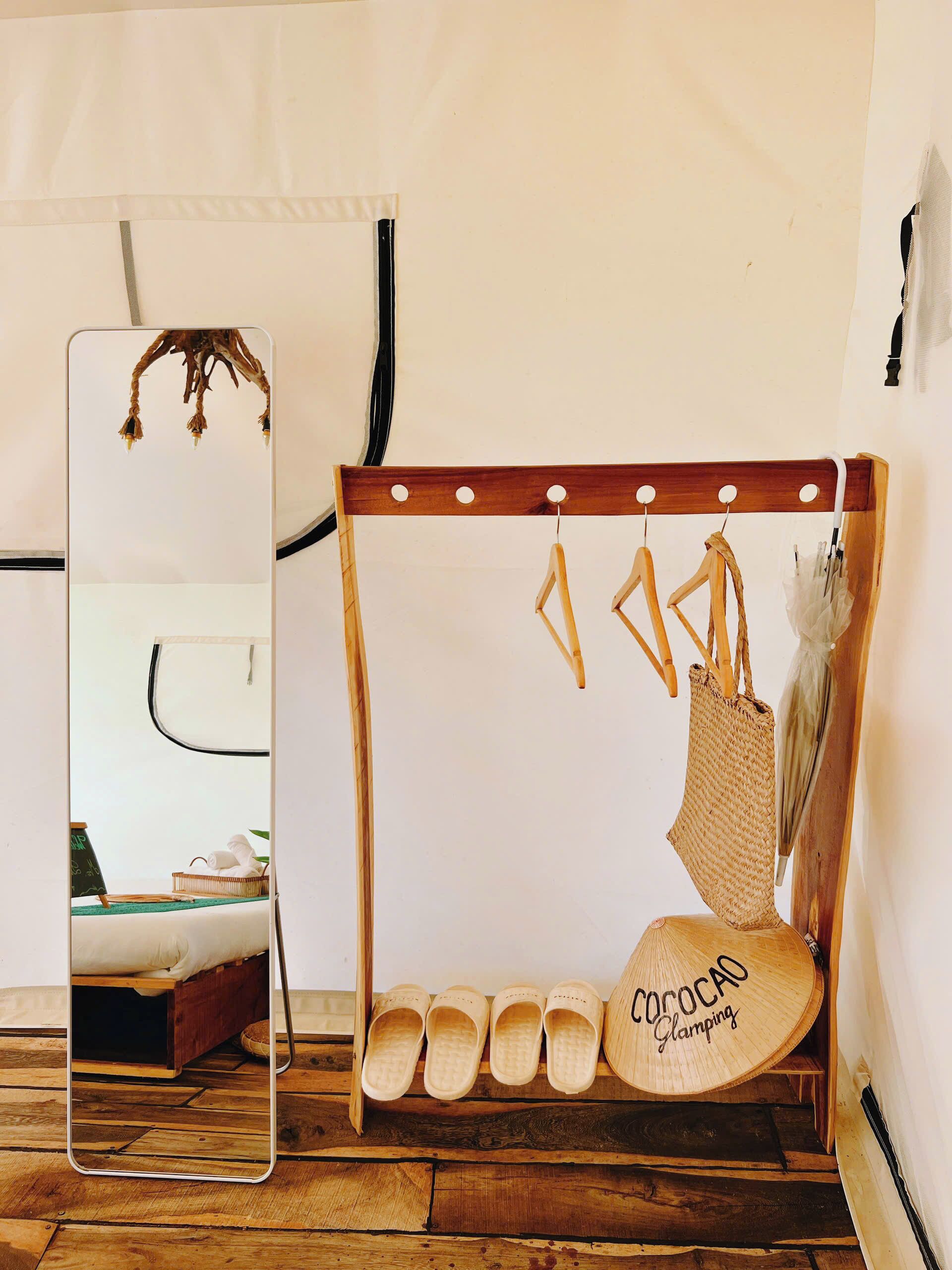 A wooden shoe rack with sandals and a woven bag hanging on hooks.