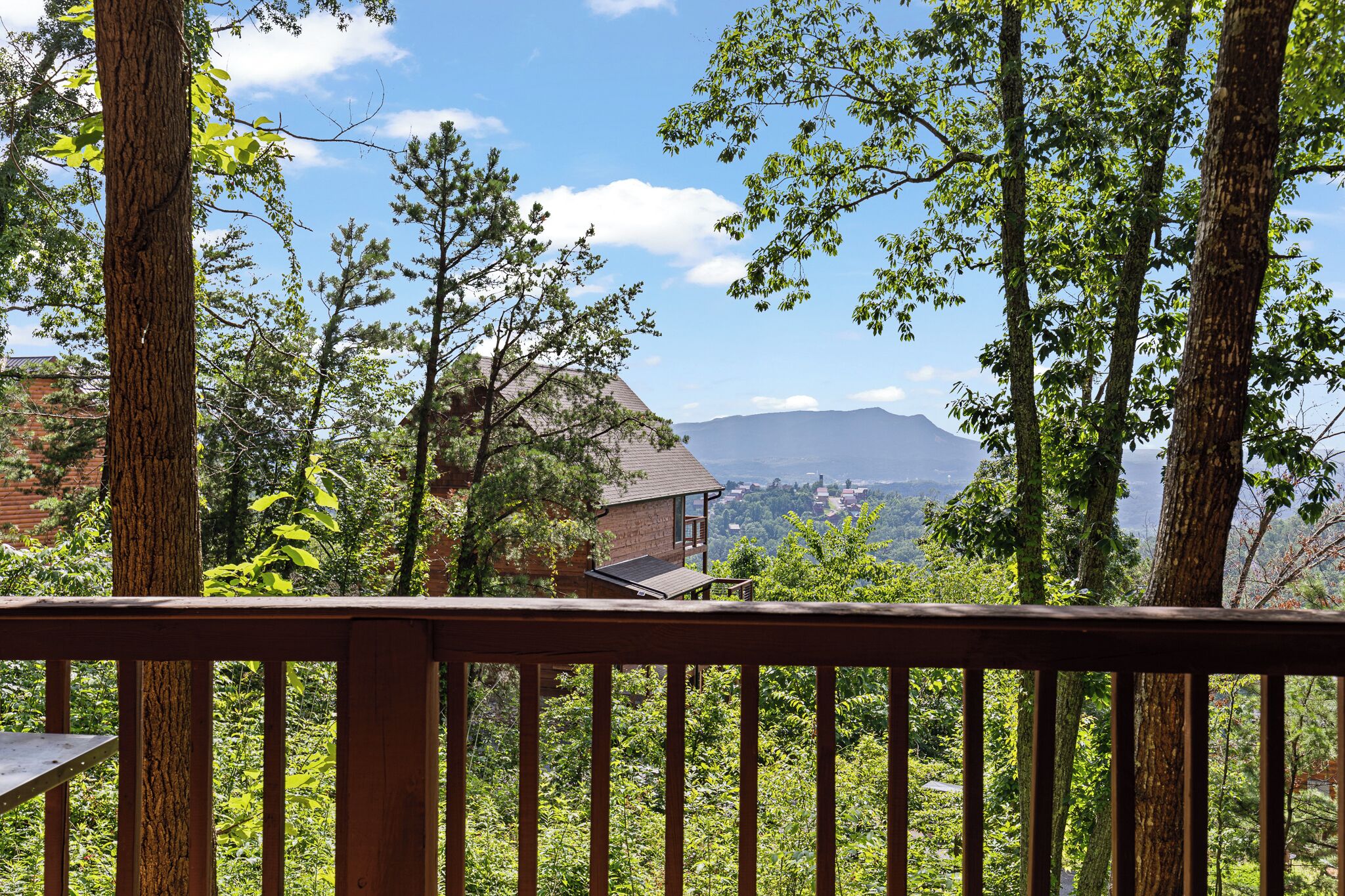 A view from a balcony overlooking a mountainous landscape with a distant town.