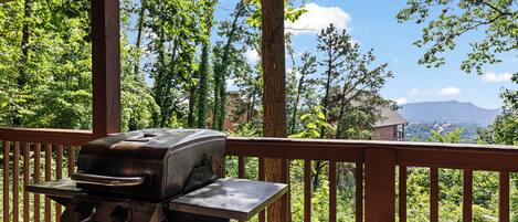 Una parrilla de barbacoa en una terraza de madera con vistas a un paisaje montañoso.