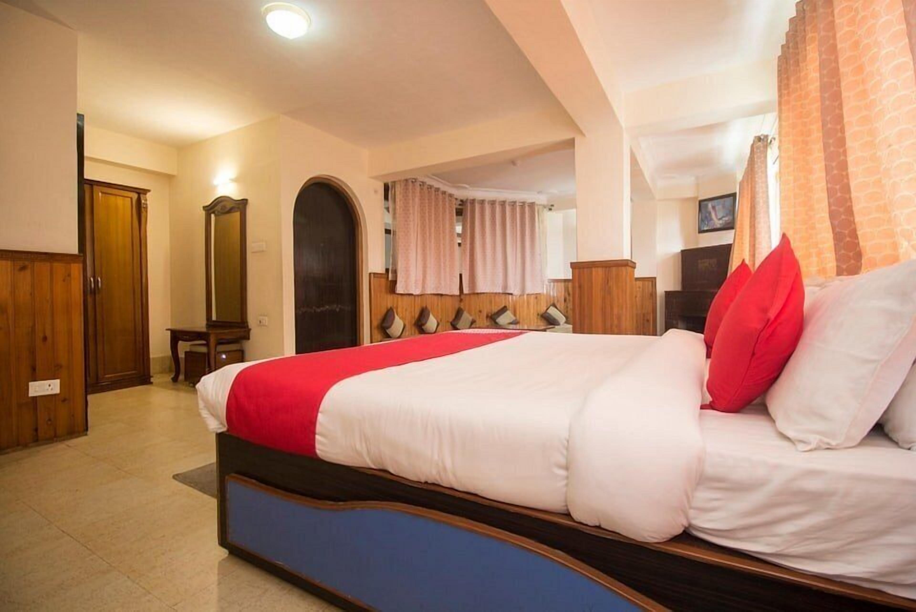 Un dormitorio con una cama grande, un armario de madera y un espejo.
