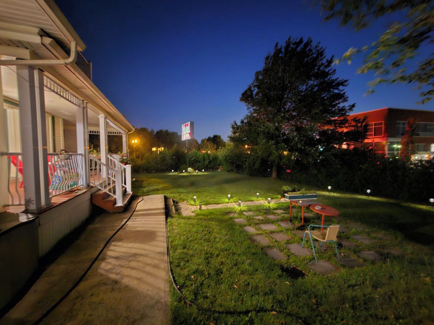 A hotel with a covered outdoor area, a lawn, and a patio with tables and chairs.