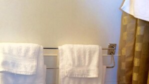 Ein Badezimmer mit weißen Handtüchern an einem Haken und einem braun-karierten Duschvorhang.
