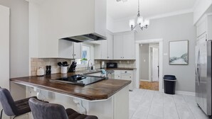 Una cocina moderna con una isla central, armarios blancos y un refrigerador de acero inoxidable.