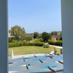 A swimming pool with multiple lanes, surrounded by greenery and a clear sky.
