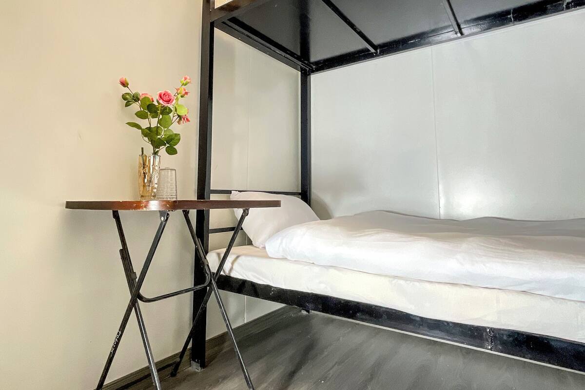 A bunk bed room with a small table and a vase of flowers.