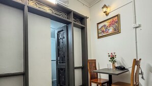 A room with a wooden floor, a dining table with chairs, an air conditioning unit, a decorative door, and a wall-mounted light fixture. - HC Luxury Apartment (Hanoi)