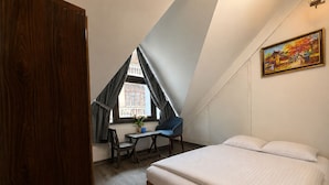 A bedroom with a bed, a desk, and a chair, a window with curtains, and a painting on the wall. - HC Luxury Apartment (Hanoi)
