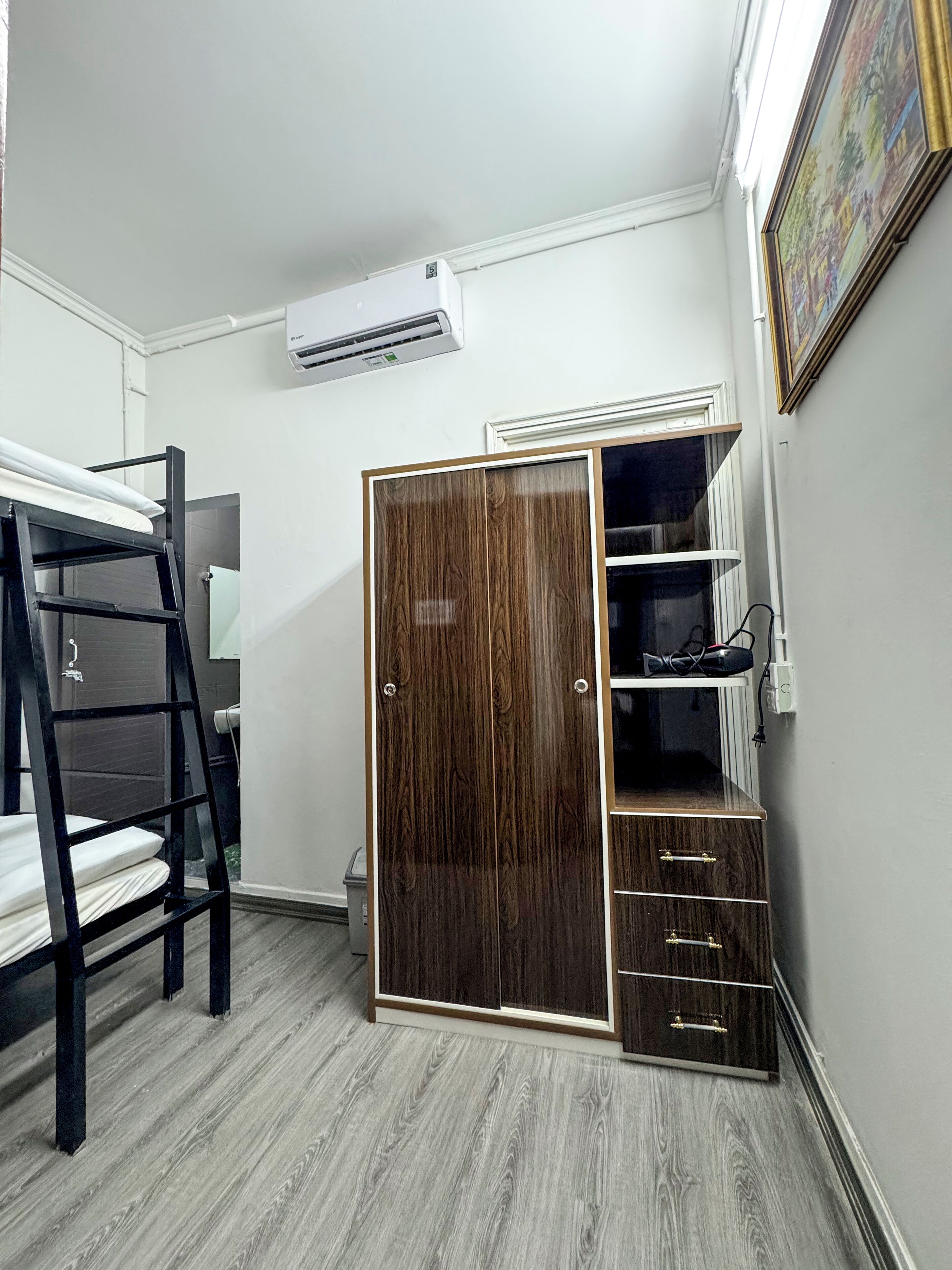 Une chambre avec un lit superposé, une armoire avec plusieurs compartiments et un appareil de climatisation.